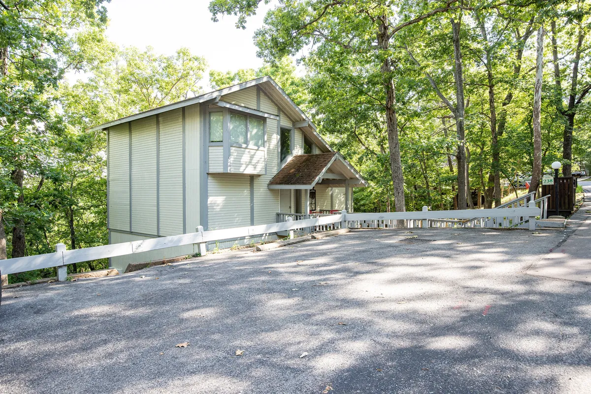 A peaceful exterior shot of the Cabernet Chalet, surrounded by mature trees and a spacious driveway. The tranquil setting hints at nature trails and outdoor activities, while the welcoming home invites relaxation after a day of exploring.