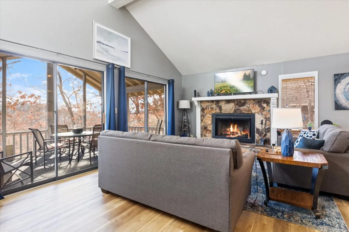 A cozy, sunlit living space featuring a crackling fireplace, plush sofas perfect for family gatherings, expansive windows framing the scenic outdoors, and a spacious dining area designed for entertaining.