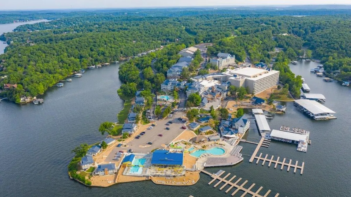 A sweeping exterior view featuring multiple swimming pools, a marina, lush greenery, and resort-style buildings with plenty of space for both relaxation and active pursuits. The pools and marina are bustling, suggesting a lively and fun atmosphere ideal for family gatherings or groups of friends.